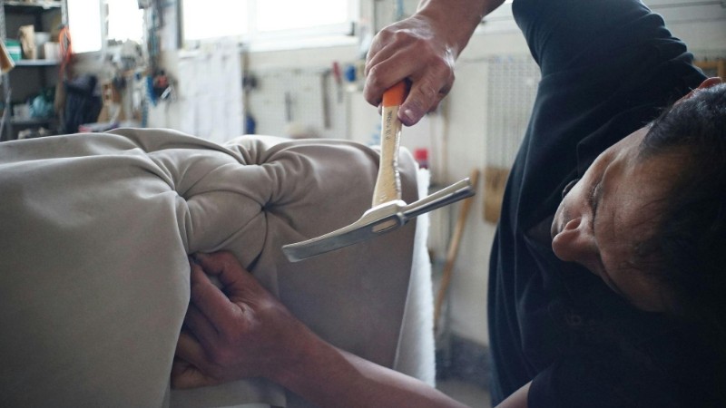 Skilled artisan working meticulously on a sofa using upholstery tools in a workshop., tags: en - pexel